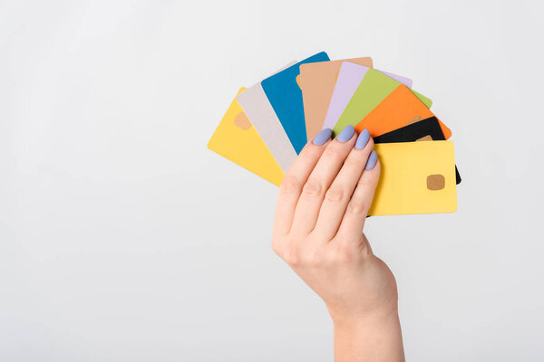 обрезанный вид женщины, держащей разноцветные шаблоны кредитных карт в руке изолированы на белом
 