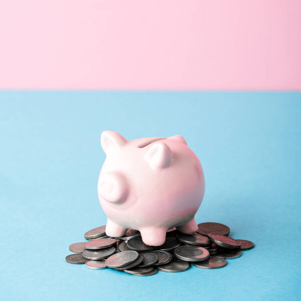 close up of coins near piggy bank isolated on blue and pink 