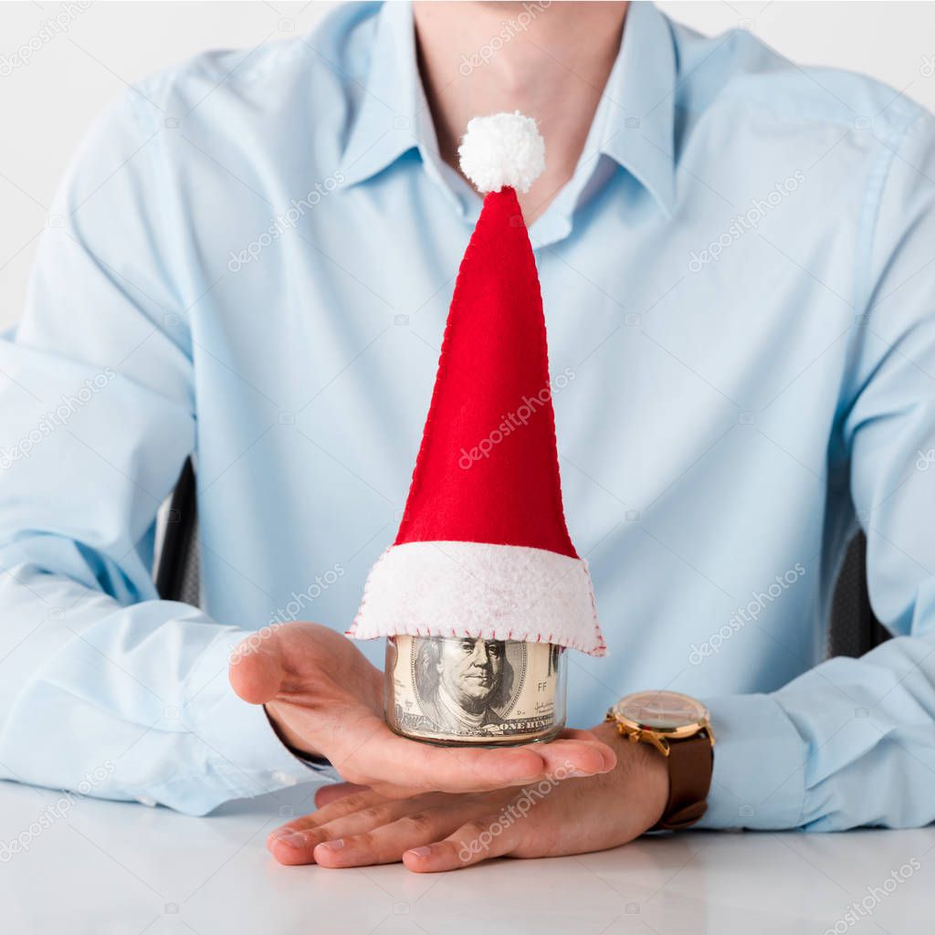 cropped view of man holding jar with dollar banknotes and santa hat isolated on white 