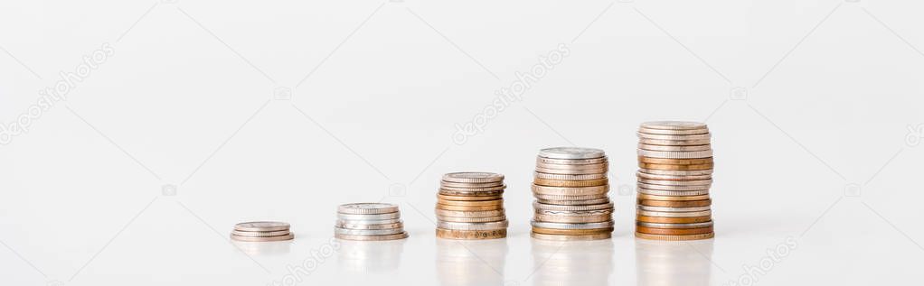 panoramic shot of stacks of silver and golden coins on white 