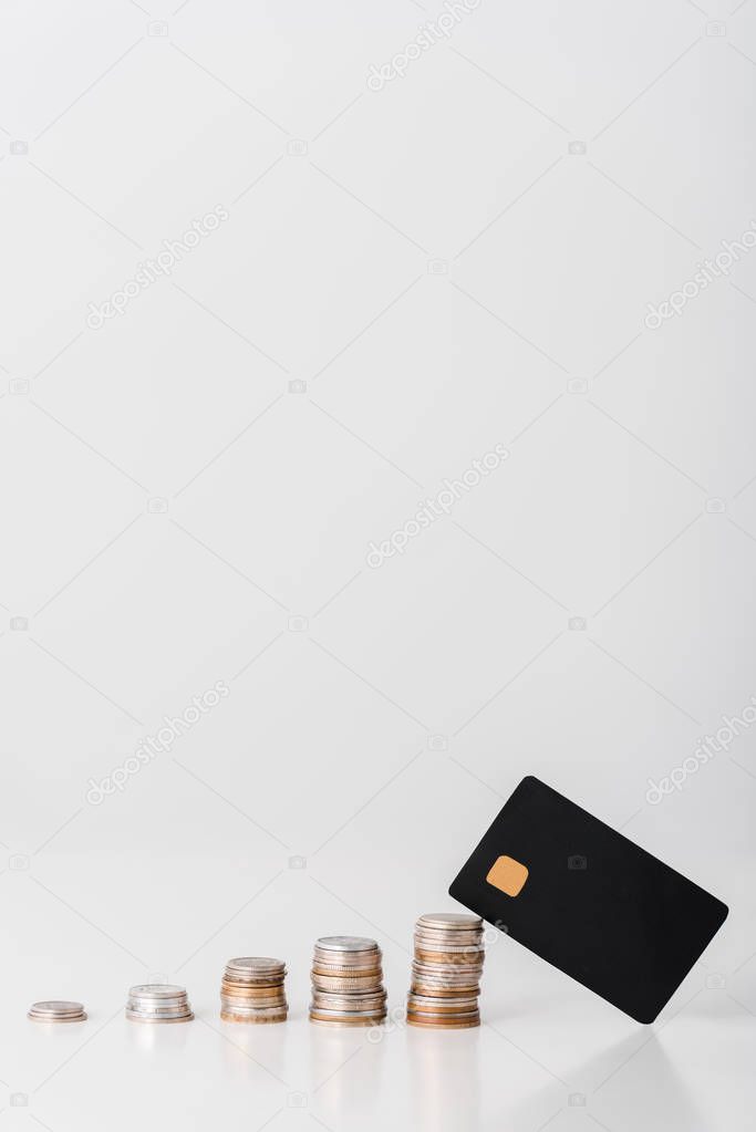 stacks of silver and golden coins near black credit card template on white 