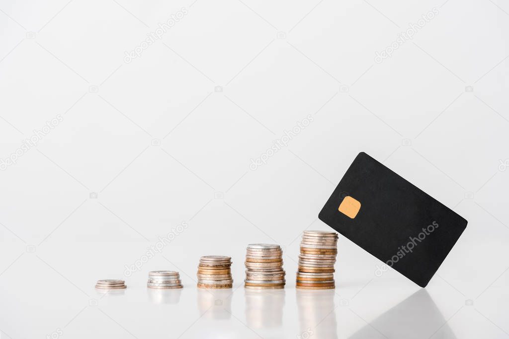 stacks of silver and golden coins near credit card template on white 