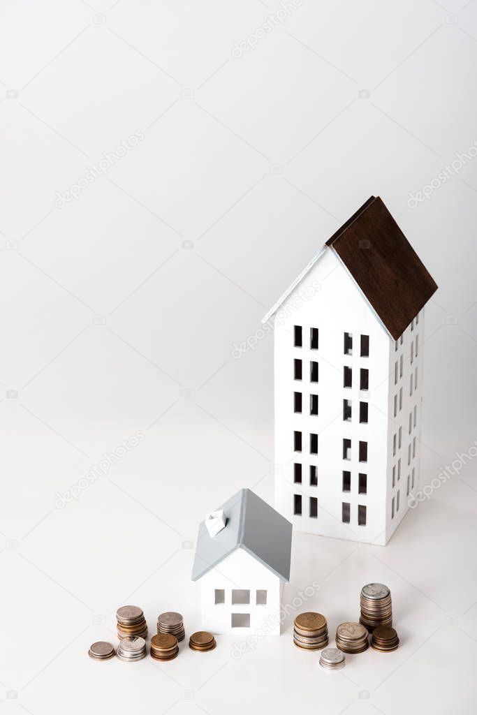 carton houses near stacks with coins on white 