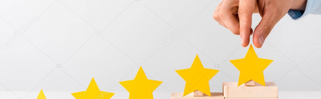 panoramic shot of man touching yellow star isolated on white 