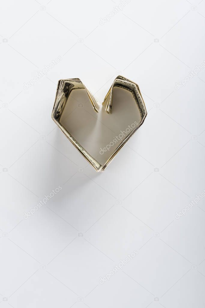 top view of heart-shaped dollar banknotes on white