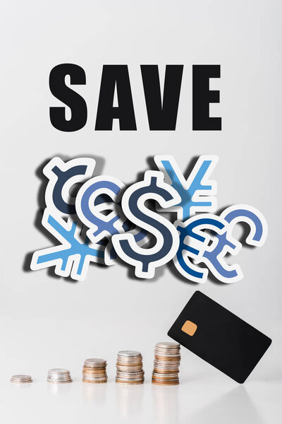 stacks of silver and golden coins near credit card template and save letters on white 