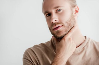 bej elbiseli genç yakışıklı adam beyaz tenli, dokunaklı yüze dokunuyor.