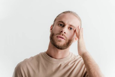 Beyazlar içinde yalnız başına bej kıyafetli genç ve yakışıklı bir adam.