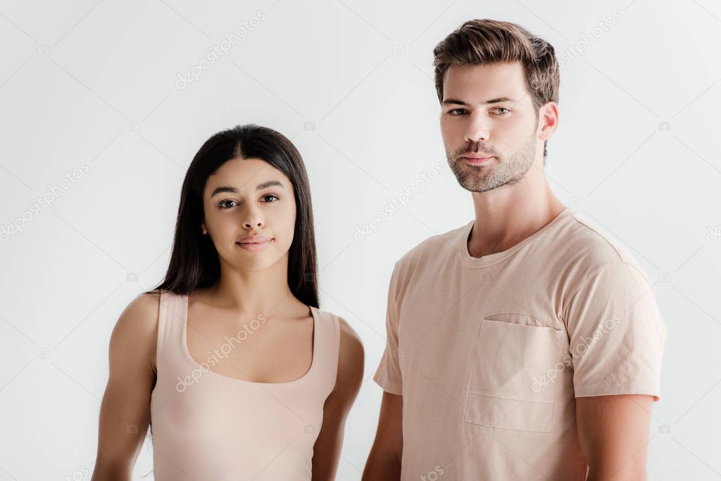 young interracial couple in beige outfit posing together isolated on white