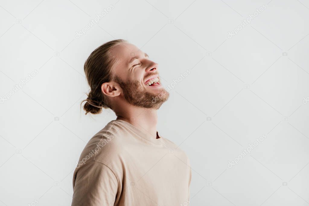 happy young handsome man in beige outfit laughing isolated on white