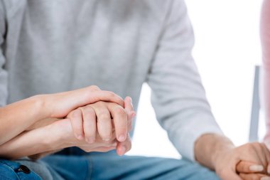 cropped view of multicultural support group holding hands isolated on white clipart