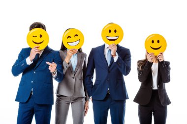 KYIV, UKRAINE - AUGUST 12, 2019: multicultural business people in suits holding emoji in front of faces isolated on white clipart