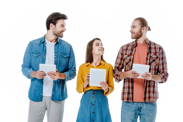 Sonriendo Tres Jóvenes Amigos Sosteniendo Tabletas Digitales Mirándose Aislados Blanco — Foto de Stock