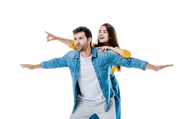 young couple in denim imitating flight and pointing with finger away isolated on white