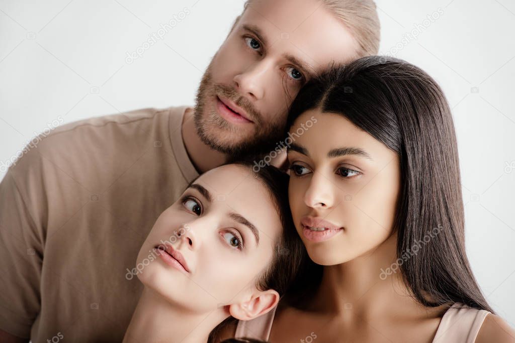young multicultural women and man in beige outfit posing together isolated on white