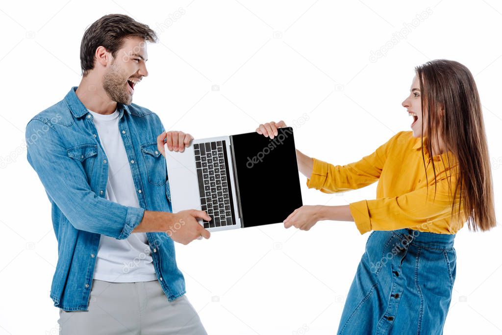 angry young couple screaming while sharing laptop isolated on white