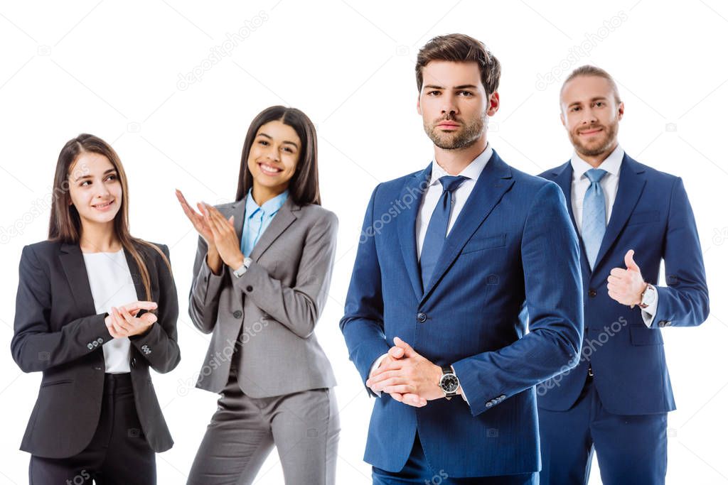 smiling multicultural business people in suits applauding confident businessman isolated on white