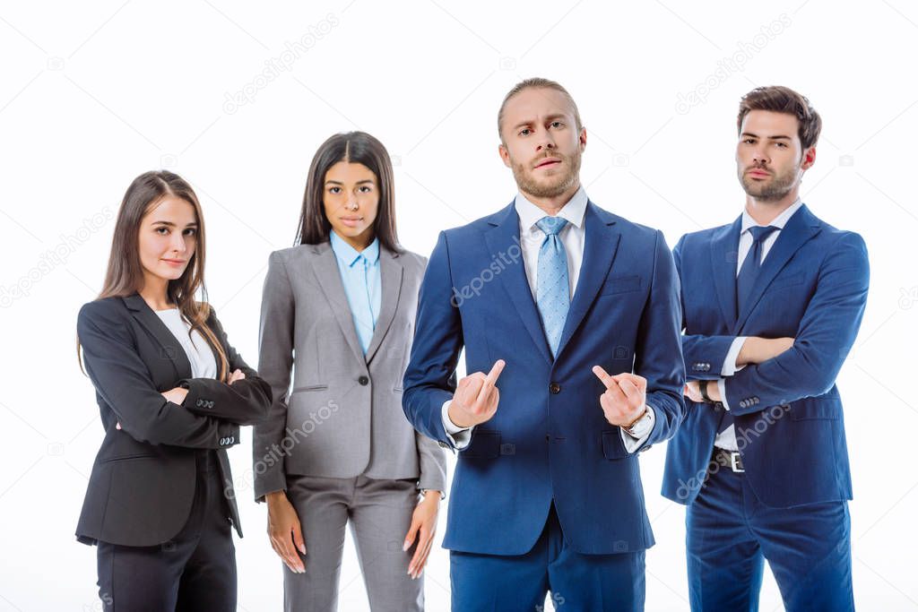 confident businessman showing middle fingers near multicultural business people in suits isolated on white