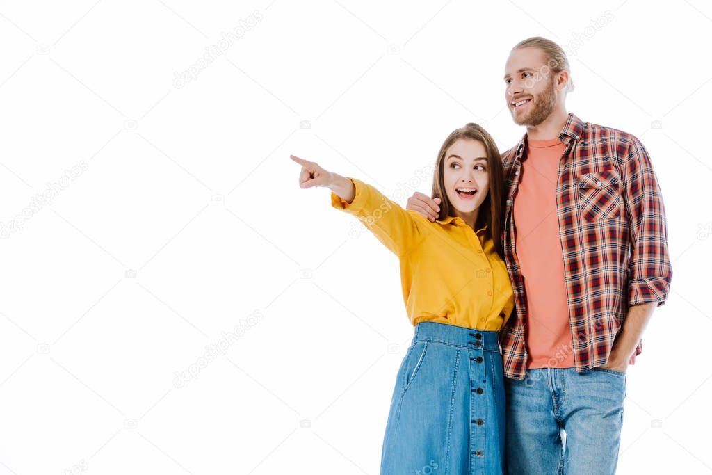 excited young couple in casual outfit pointing with finger away isolated on white