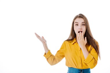 Şaşırmış çekici bir kız, ağzı açık, elleri beyaza ayrılmış bir şekilde işaret ediyor.