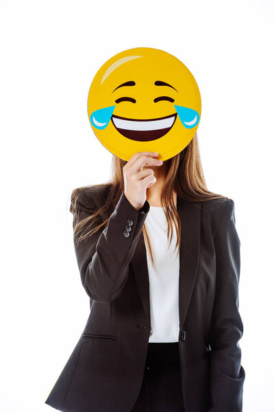 KYIV, UKRAINE - AUGUST 12, 2019: businesswoman in suit holding Face With Tears of Joy emoji in front of face isolated on white