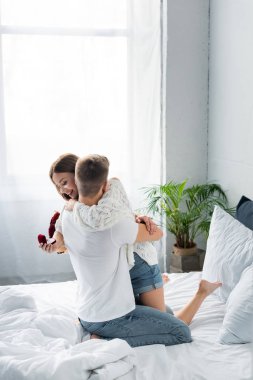 Buketli bir adam ve gülümseyen bir kadının ona kutuyla sarılmasının arkası. 