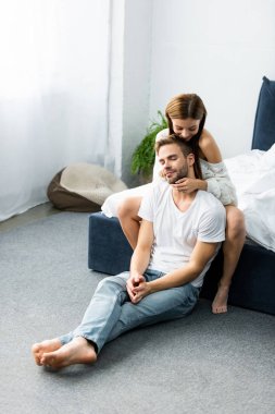 Çekici ve gülümseyen bir kadın. Gözleri kapalı yakışıklı bir adama sarılıyor. 