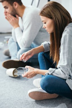 Seçici odak noktası, cam tutan çekici bir kadın ve arka planda şok olmuş bir adam. 