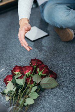 cropped view of man and flowers on floor in robbed apartment  clipart