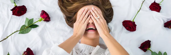 Πανοραμική Λήψη Χαμογελαστή Γυναίκα Συσκοτίζοντας Πρόσωπο Και Ξαπλωμένη Στο Κρεβάτι — Φωτογραφία Αρχείου