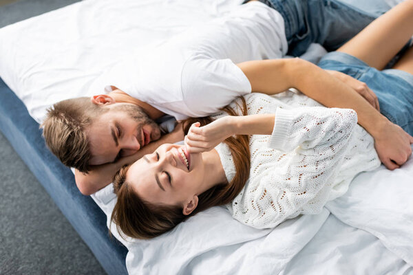 high angle view of handsome man hugging attractive and smiling woman in apartment 