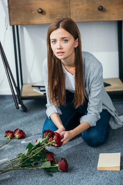 奪われたアパートに花を持つ魅力的で悲しい女性 — ストック写真