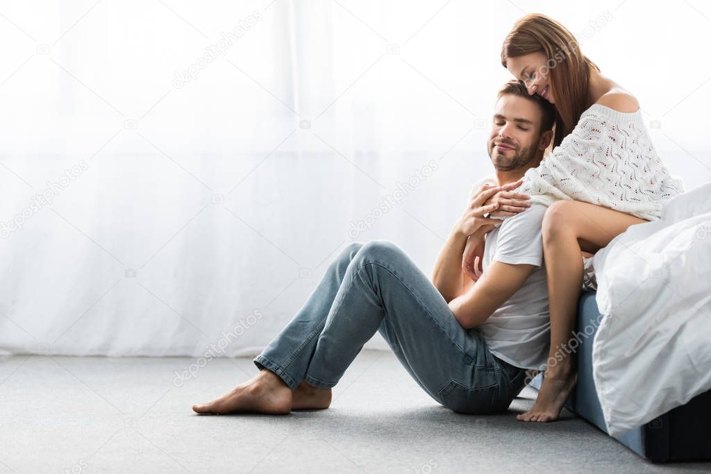 attractive and smiling woman hugging handsome man with closed eyes 