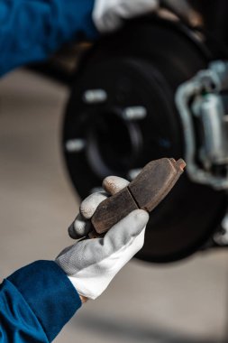 cropped view of mechanic holding brake pad near assembled disc brakes clipart