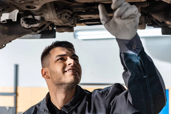 Concentrated Mechanic Examining Raised Car Workshop — Stock Photo, Image