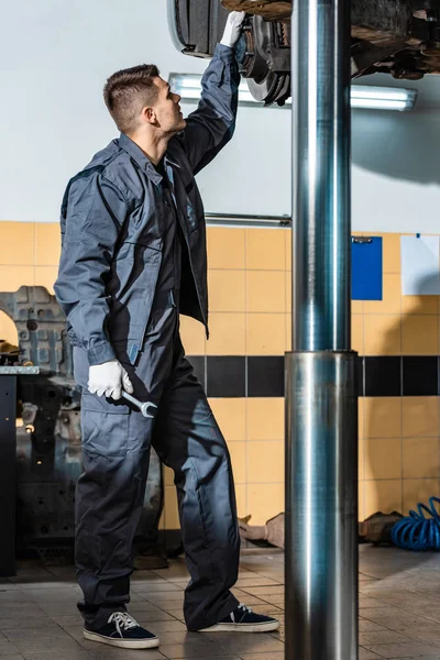 Young Mechanic Inspecting Raised Car Workshop — Stock Photo, Image