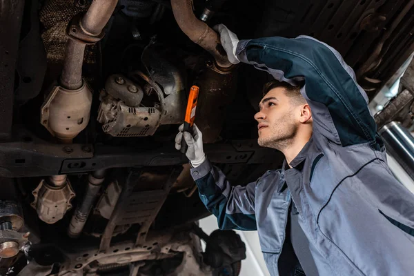 Aufmerksame Mechaniker Inspizieren Boden Des Autos Mit Taschenlampe — Stockfoto