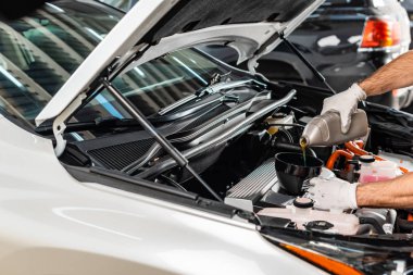 Araba motoruna motor yağı döken tamircinin kısmi görüntüsü