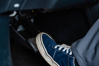 partial view of mechanic in sneakers pressing brake pedal in car clipart