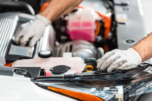 cropped view of mechanic inspecting car engine compartment 