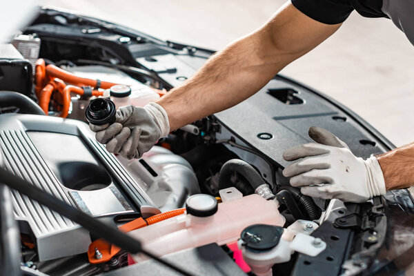 cropped view of mechanic holding oil cap near motor compartment