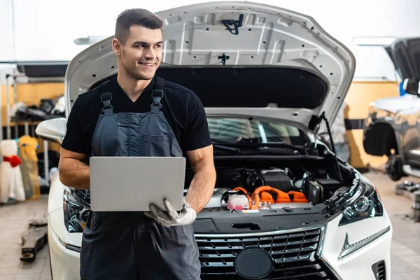 Jóképű Szerelő Gazdaság Laptop Miközben Áll Közel Autó Nyitott Motorháztető — Stock Fotó