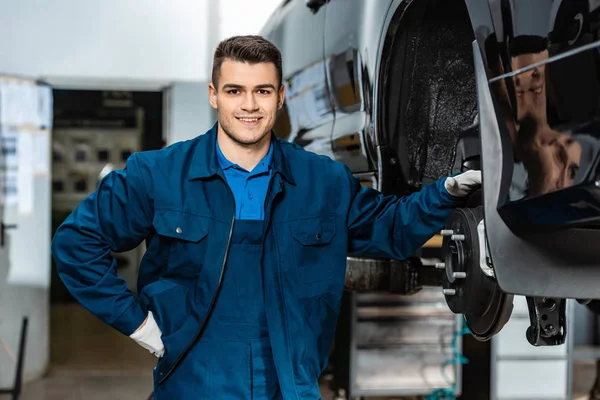 Lächelnder Mechaniker Blickt Die Kamera Während Scheibenbremsen Des Autos Berührt — Stockfoto