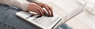 Cropped view of woman typing on laptop keyboard, panoramic shot clipart