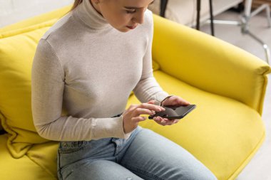 Kanepede boş ekranlı akıllı telefon kullanan bir kızın yüksek açılı görüntüsü