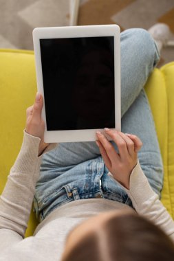 Dijital tablet kullanan ve kanepesinde boş ekran olan bir kızın genel görünümü