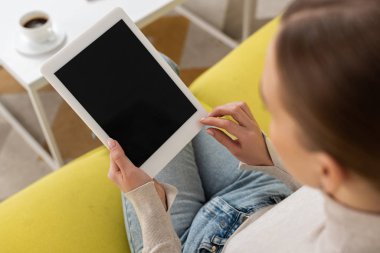 Kanepede boş ekranlı dijital tablet kullanan bir kadının genel görünümü