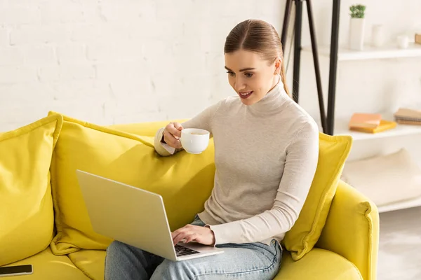 Smiling Young Woman Drinking Coffee Using Laptop Sofa — Stock Photo, Image