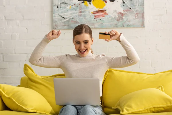 Cheerful Girl Credit Card Looking Laptop Sofa Home — Stock Photo, Image