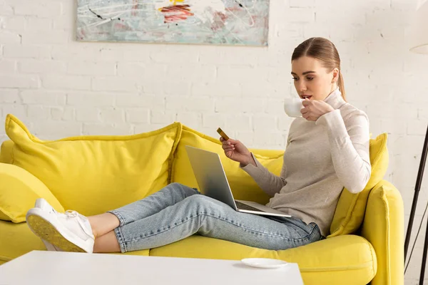 Junge Frau Trinkt Kaffee Hält Kreditkarte Der Hand Und Benutzt — Stockfoto